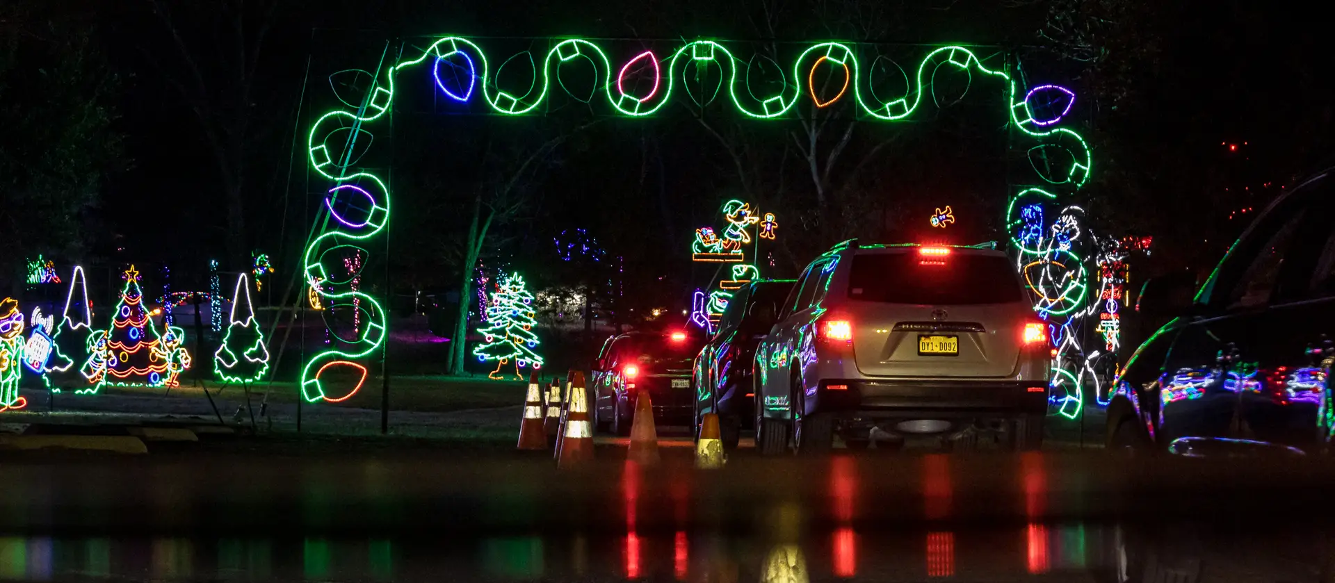 Cars driving beneath string light arches at Lights of Joy Christmas Drive-Thru in Branson, MO