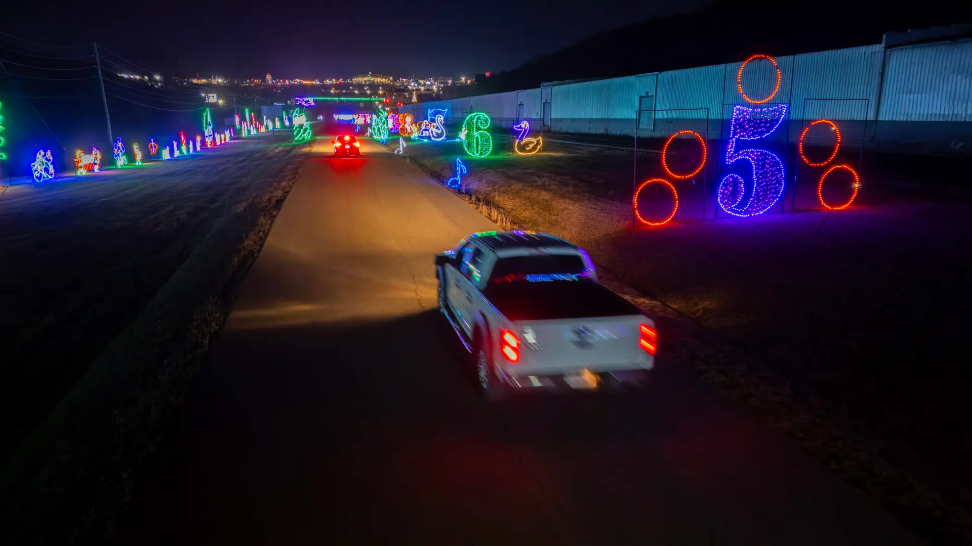 A truck driving past the five golden rings light display at Lights of Joy in Branson, Missouri