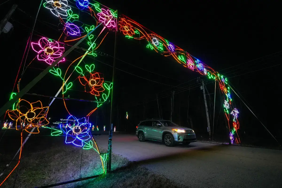 A car driving under the floral light arch at Lights of Joy Christmas Drive-Thru in Branson